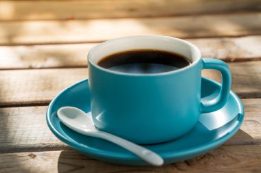 Eski ahşap zeminde mavi seramik kahve fincanı. Yumuşak odaklanma. Sığ odak etkisi.