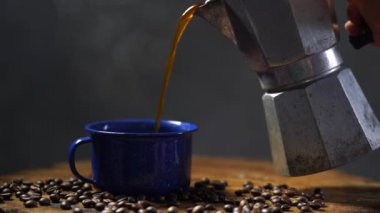 Eski ahşap zeminde kahve çekirdeği ve dumanlı bir bardak mineli kahve. Esrarlı kahve seti. yumuşak odak.