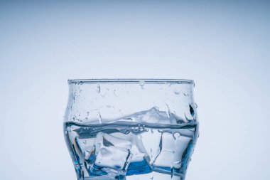 Buz küpü su bardağına düştü. Temiz bardaktan su sıçradı. Taze konsept