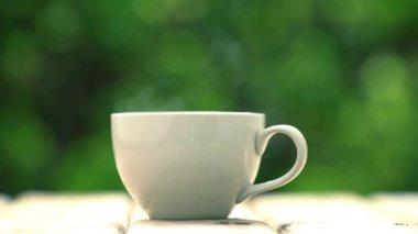 white ceramic coffee mug On the wooden floor, green tree bokeh background
