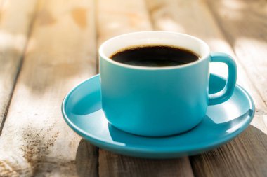 Eski ahşap zeminde mavi seramik kahve fincanı. Yumuşak odaklanma. Sığ odak etkisi.