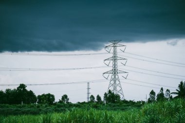 Yağmurdan önce siyah bulutlar ve pirinç tarlalarının yakınında yüksek voltaj direkleri.