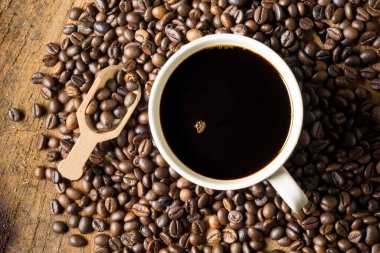 Beyaz seramik bardakta sade kahve. Kahve çekirdeklerinin üzerinde. Yumuşak odaklanma. Sığ odak etkisi.