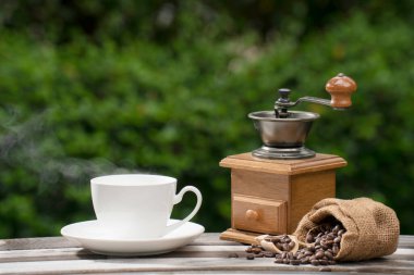 coffee cup with a grinder, Dark Coffee beans on the old wooden floor,  Close up of seeds of coffee in a natural background. 