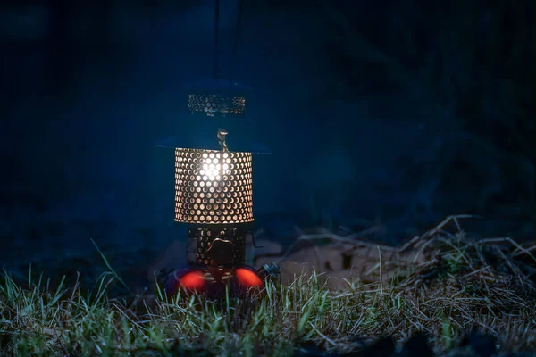 Ancient oil lamp on the grass in the dark forest at night, Night camping lantern, Isolated on Green grass background.
