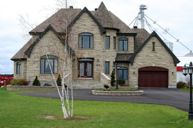 Executive stone house with turret and circular driveway clipart