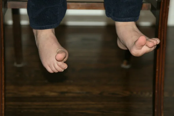 Pequenos dedos dos pés tortos de uma cadeira Imagem De Stock