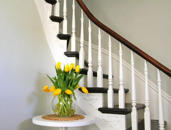 Yellow tulips on a round table beside heritage staircase — Stock Photo, Image