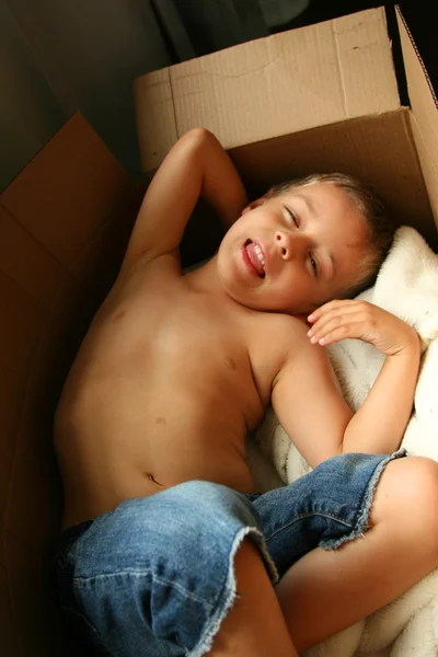 Jongen liggend in een kartonnen doos — Stockfoto