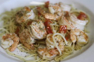 Spaghetti alla olio with shrimp in white shallow bowl