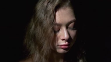 Uzun açık kahverengi saçlı, gri gözlü, beyaz bardaktan zevk alarak kahve içen bir kızın yakın çekimi. Siyah bir arkaplanda tam yüz olarak çekilen