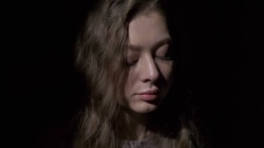 Uzun açık kahverengi saçlı, gri gözlü, beyaz bardaktan zevk alarak kahve içen bir kızın yakın çekimi. Siyah bir arkaplanda tam yüz olarak çekilen