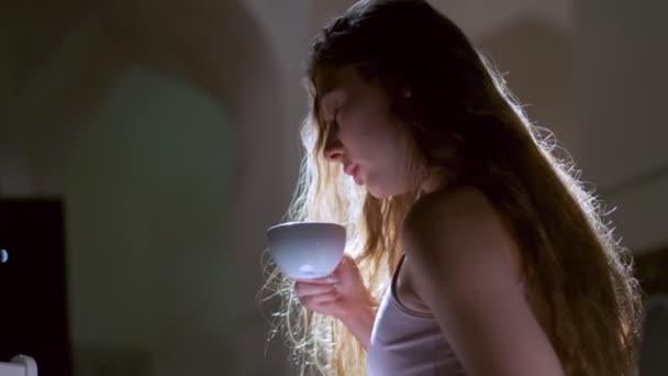 머리에 드레스를 속눈썹을 소녀가 컵에서 즐거움을 느끼며 커피를 마시고 측면에서 — 비디오