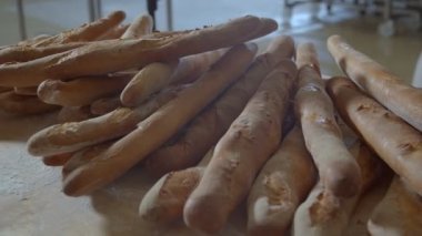 Cart with fresh baked raisin bread is taken out of the oven woman baker dressed in white. Camera films from side-back