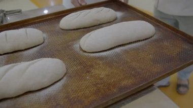 Fırın tepsisindeki fırına hazır ekmeğin kapağı metal masadan alınır. Yavaş çekim