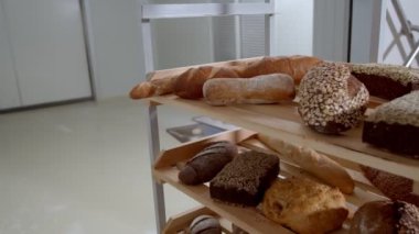 Fresh baked long baguette breads lie on the wooden table sprinkled with flour in a pile. Slow motion