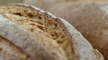 Camera is zoom through sliced and whole wheat bread and wheat ears to the clay pots placed on the wooden table and then zoom out