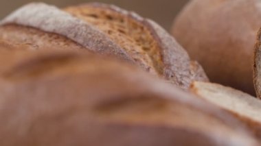 Camera is zoom through sliced and whole wheat bread and wheat ears to the clay pots placed on the wooden table and then zoom out