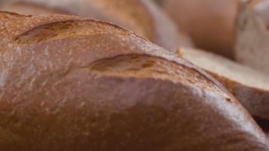 Camera is zoom through sliced and whole wheat bread and wheat ears to the clay pots placed on the wooden table and then zoom out