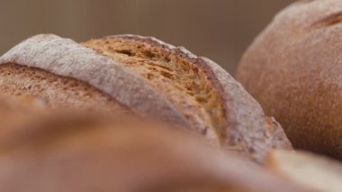 Camera is zoom through sliced and whole wheat bread and wheat ears to the clay pots placed on the wooden table and then zoom out