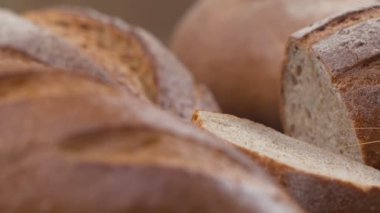 Camera is zoom through sliced and whole wheat bread and wheat ears to the clay pots placed on the wooden table and then zoom out