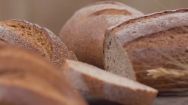 Camera is zoom through sliced and whole wheat bread and wheat ears to the clay pots placed on the wooden table and then zoom out