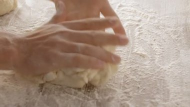 Male hands divide baking dough into three equal shares on a wooden board sprinkled with flour. Filmed on black background