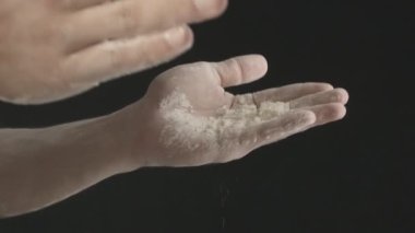Erkek ellerinin un sallamasını yakından çek. Siyah bir arkaplanda çekilmiş.