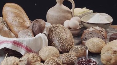 Different types of fresh baked Dutch bread is on the wooden table. wicker basket stands on the side