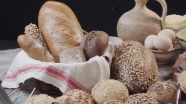 Different types of fresh baked Dutch bread is on the wooden table. wicker basket stands on the side