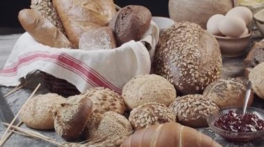 Different types of fresh baked Dutch bread is on the wooden table. wicker basket stands on the side