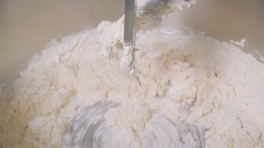 Container of big bakery mixer and mixer blades are cleaned of of dough residues