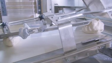 Dough pieces on the working conveyor line of dough machine in a bakery. Slow motion