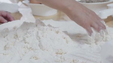 Tahta masadaki un yığınına yumurta karıştırıp hamuru yoğurmak. Yavaş çekim