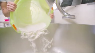 Pouring flour into a large industrial mixer at a bread baking plant