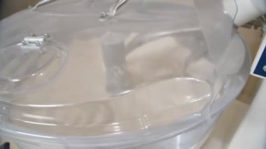 Close-up of working mixer with closed transparent lid as a part a dough machine in a bakery. Slow motion