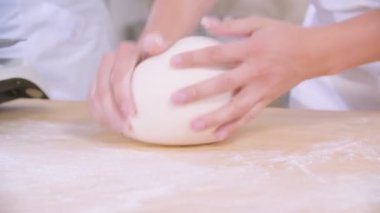 Close-up of dough kneaded by baker on a wooden board sprinkled with flour. Slow motion