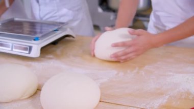 Close-up of dough kneaded by baker on a wooden board sprinkled with flour. Slow motion