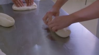 Close-up of dough kneaded by baker on a wooden board sprinkled with flour. Slow motion