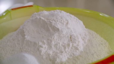 Pile of flour in a light green plastic bowl in the bakery. Slow motion