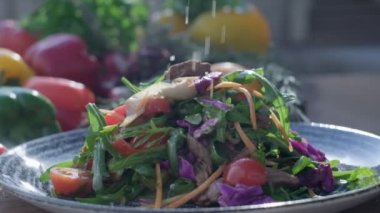 Close-up of coarsely chopped Caesar salad with chicken fillet in the ceramic dish is is sprinkled by hand with very finely grated cheese, which crumbles in all directions