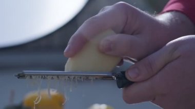 Close-up of hard cheese is grated on a small grater holding in hands. Slow motion