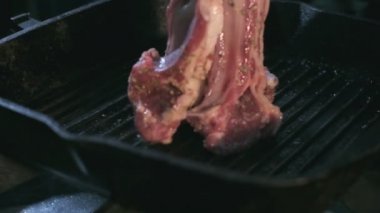 Close-up of raw lamb ribs in spices being thrown vertically to the hot grill. Slow motion