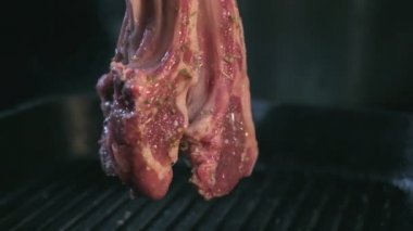 Close-up of raw lamb ribs in spices being thrown vertically to the hot grill. Slow motion