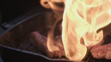 Close-up of lamb ribs in spices on a grill are being flamed by gas burner. Slow motion