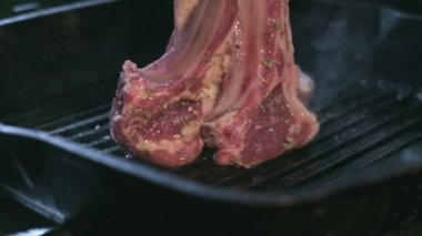 Close-up of still raw lamb ribs in spices are grilled. Slow motion