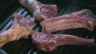 Close-up of still raw lamb ribs in spices are grilled. Slow motion
