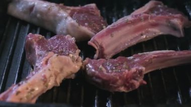 Close-up of still raw lamb ribs in spices are grilled. Slow motion