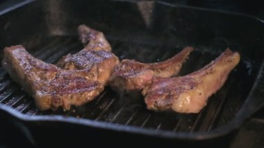 Close-up of still raw lamb ribs in spices are grilled. Slow motion