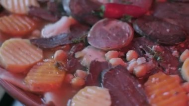 Close-up of national Kazakh dish Beshbarmak made of veggies, dough and horsemeat served in deep clay dish with hot red pepper on top